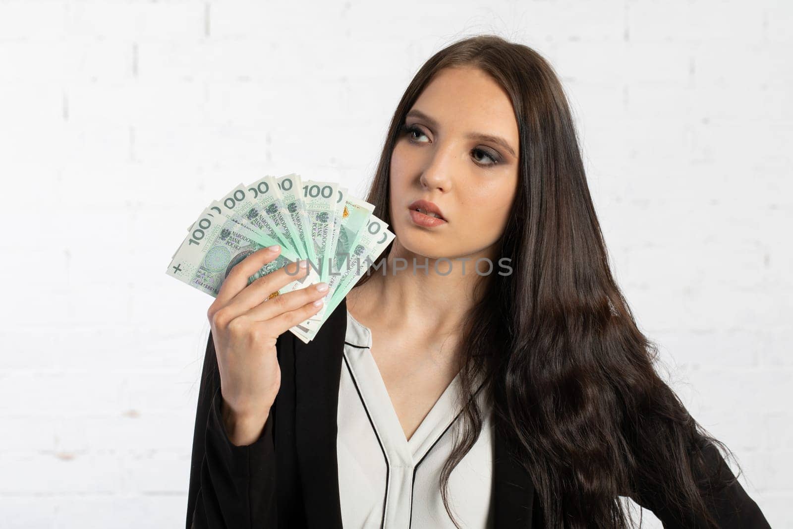 A young successful woman is holding a large amount of cash.