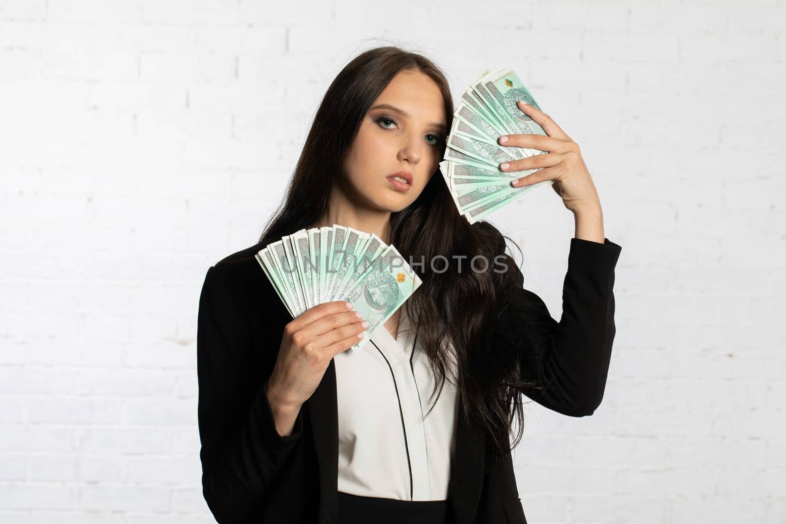 A young successful woman is holding a large amount of cash.