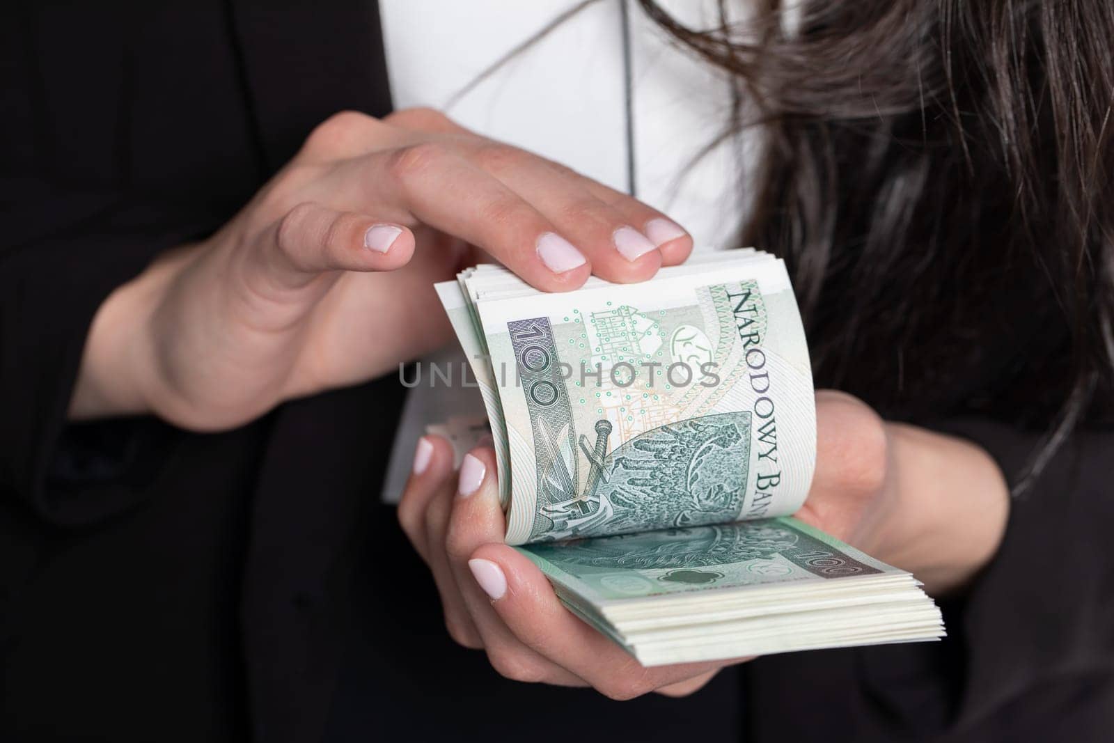 A close up shot when a businesswomen counts a thick stack of banknotes in Polish denomination.