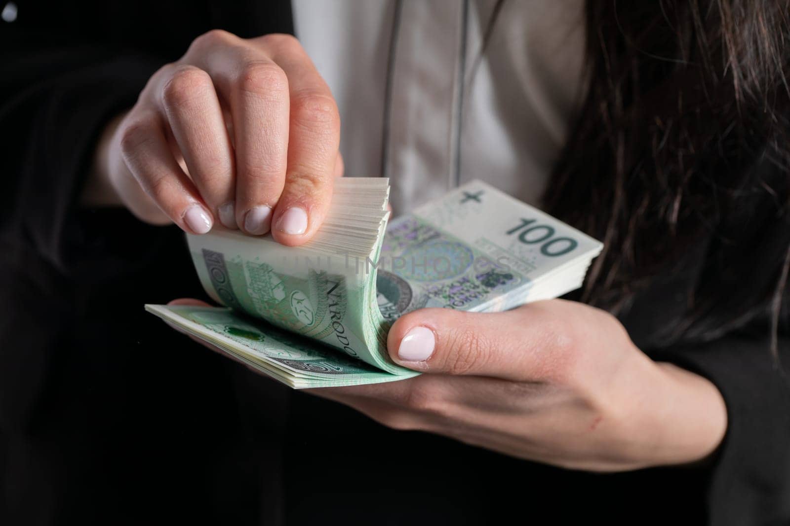 A close up shot when a businesswomen counts a thick stack of banknotes in Polish denomination.
