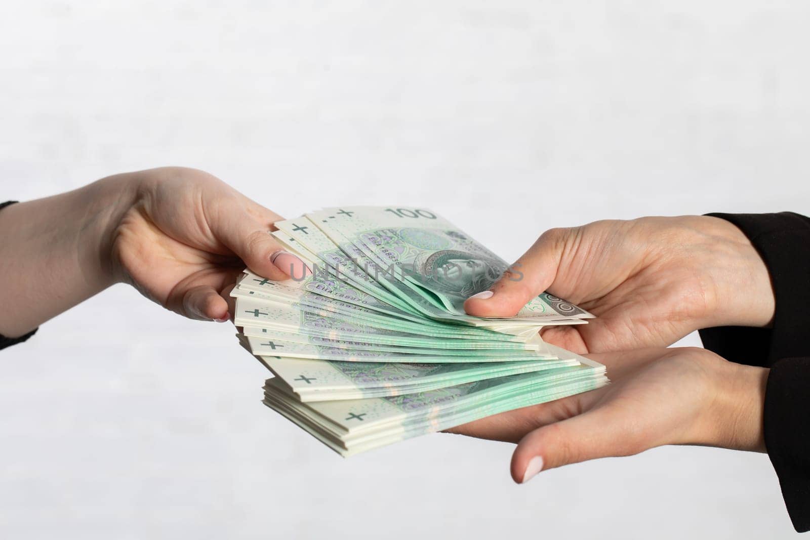 Spread-out fan-shaped paper banknotes hold young woman's hands.