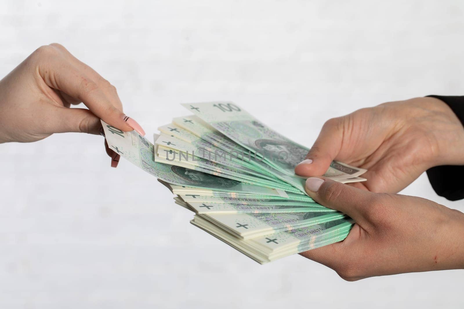 Spread-out fan-shaped paper banknotes hold young woman's hands.
