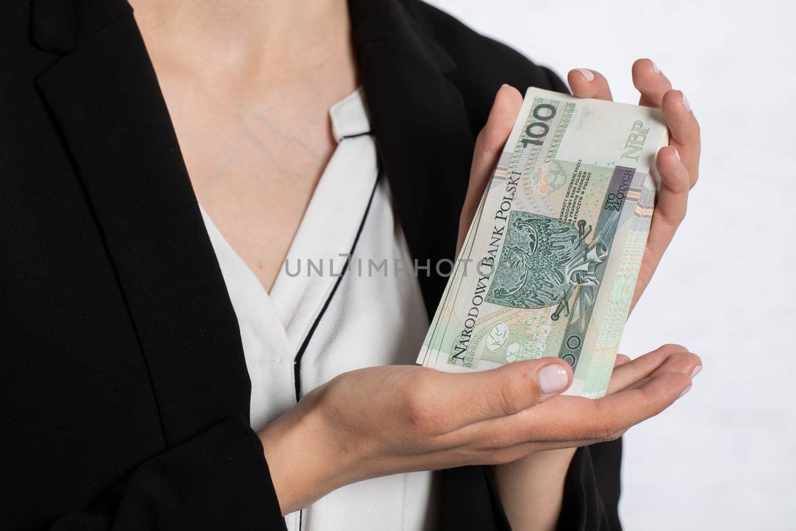A young teenager holds in her hands money with a face value of one hundred Polish zlotys.