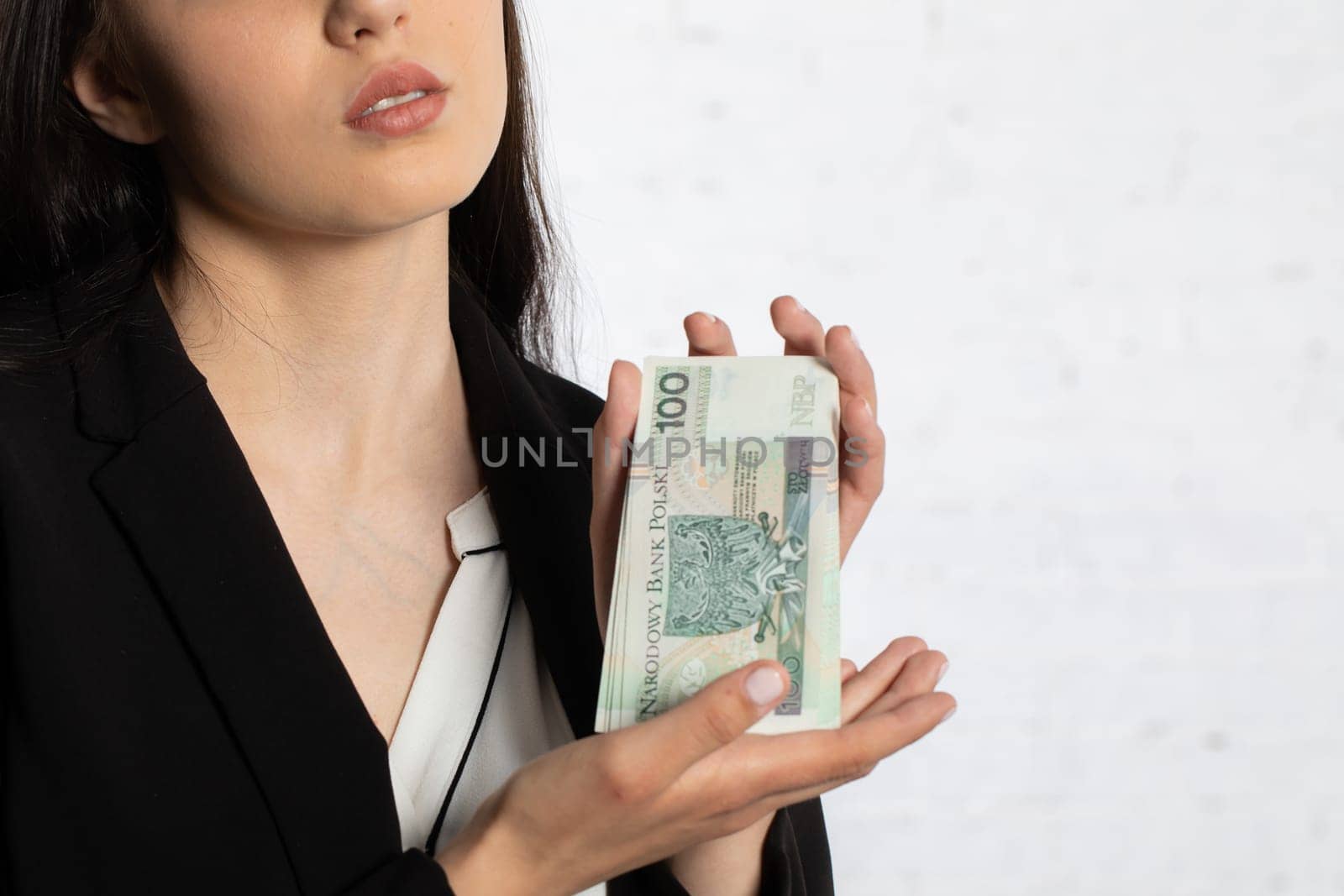 A young teenager holds in her hands money with a face value of one hundred Polish zlotys.