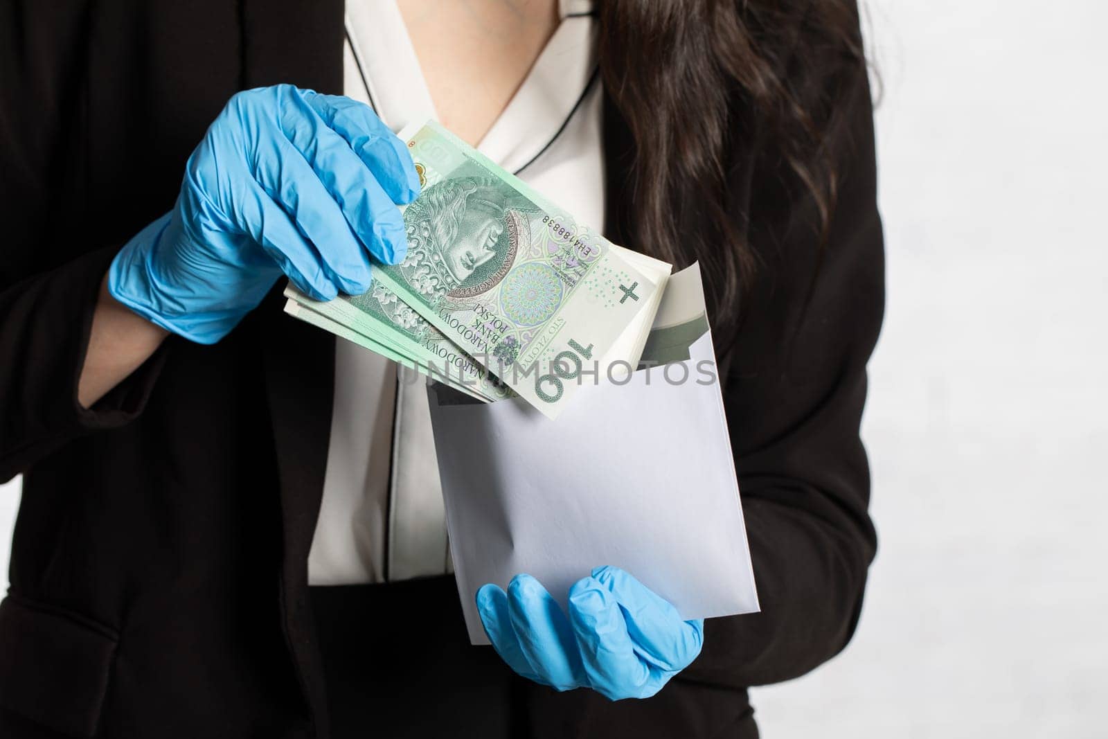 The woman slips a bundle of one hundred Polish zloty banknotes into a white envelope.