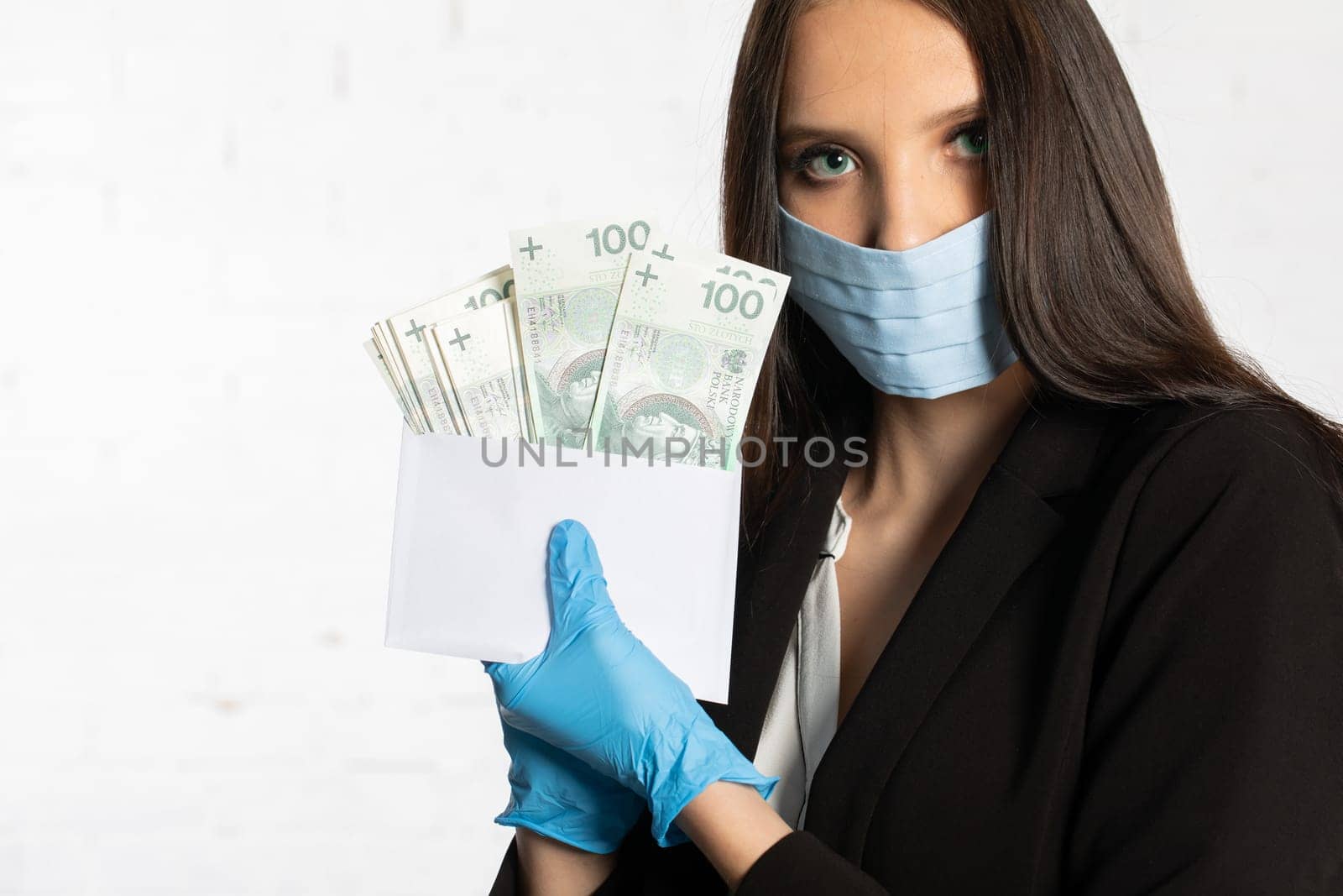 The woman slips a bundle of one hundred Polish zloty banknotes into a white envelope.