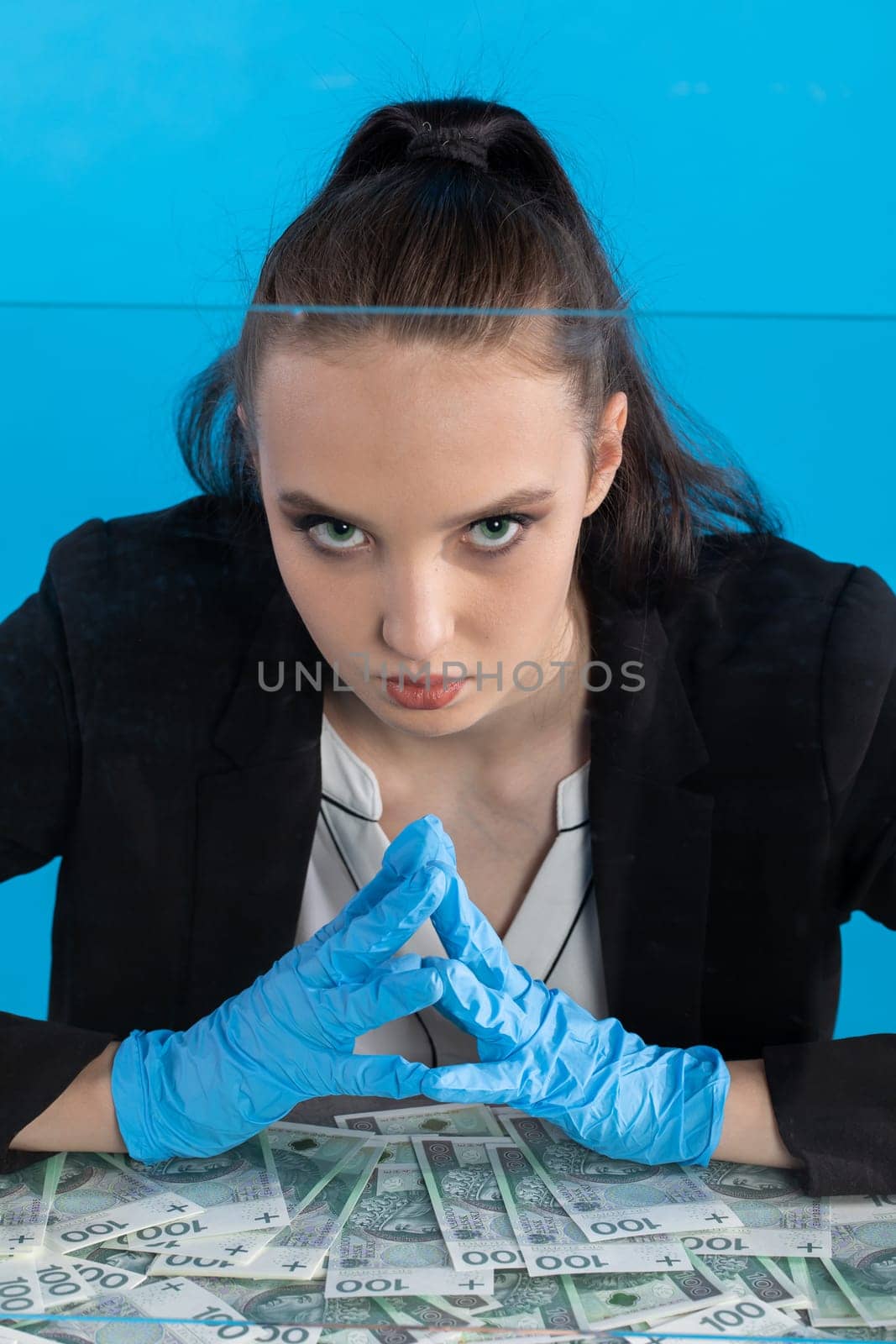 The cashier has randomly distributed banknotes on the desk behind the glass and tries to count them all exactly.