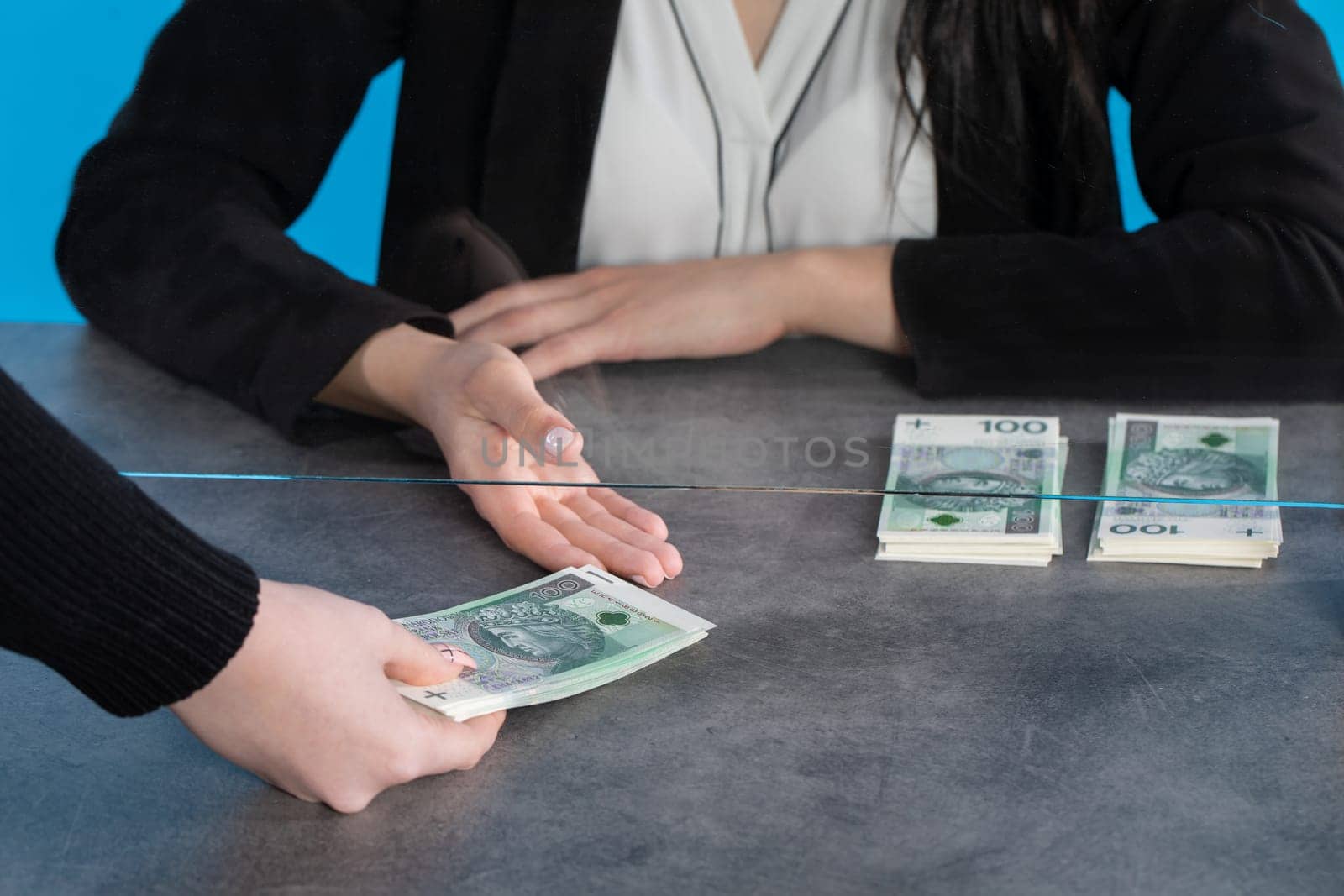 At a bank position, an employee accepts large sums of money from a young woman.