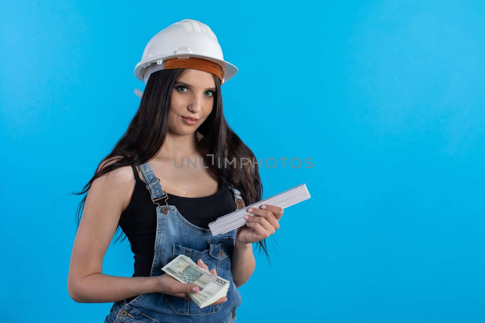A woman in a hard hat holds a bundle of banknotes in her hand and encourages cooperation.