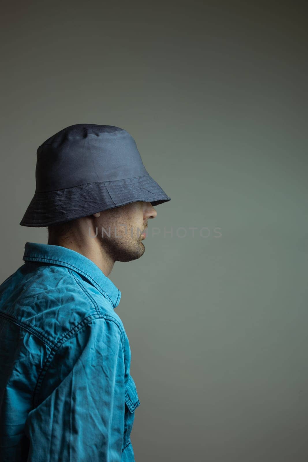 Hipster bearded man wearing a blue shirt and dark hat looking away by Pukhovskiy