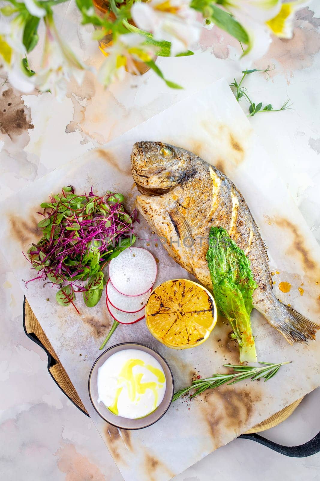 Grilled fish Dorado with lemon and herbs on a white background top view. by Pukhovskiy