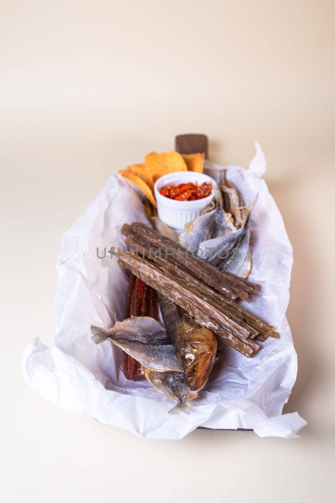 The smoked fish includes salmon, trout, and whitefish. The fish is served on a wooden board with a bowl of red pepper flakes.