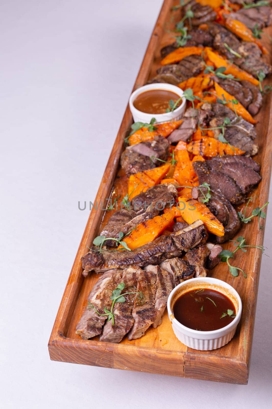 Wooden tray with delicious sliced beef and pumpkin by Pukhovskiy