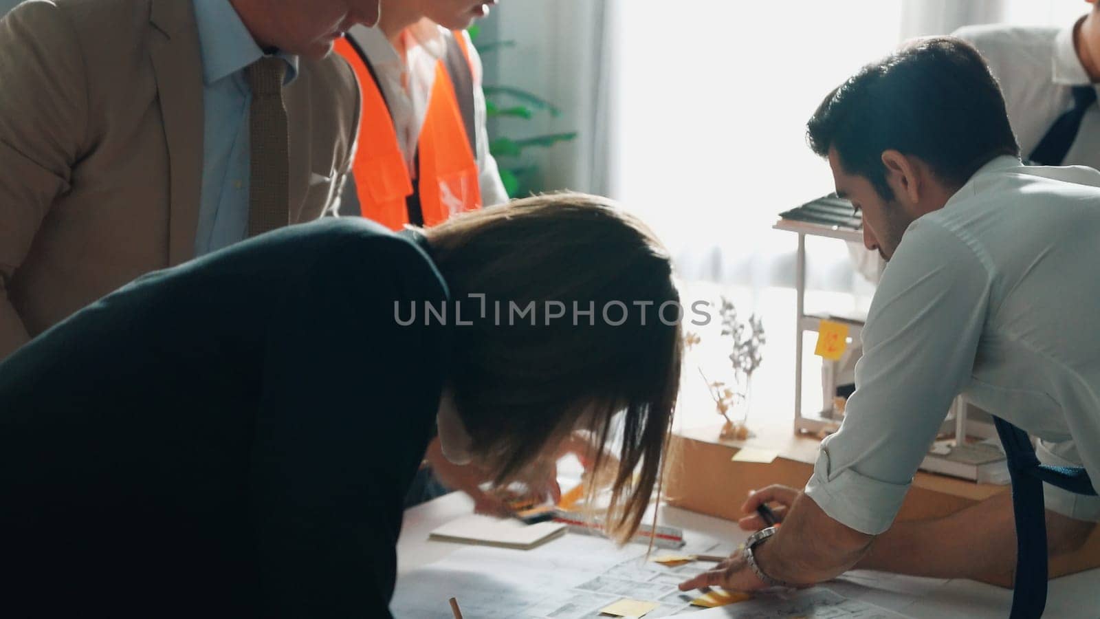 Top view of professional architect engineer team inspect house model while manager holding blueprint and asking about building construction. Group of diverse engineer working together. Alimentation.