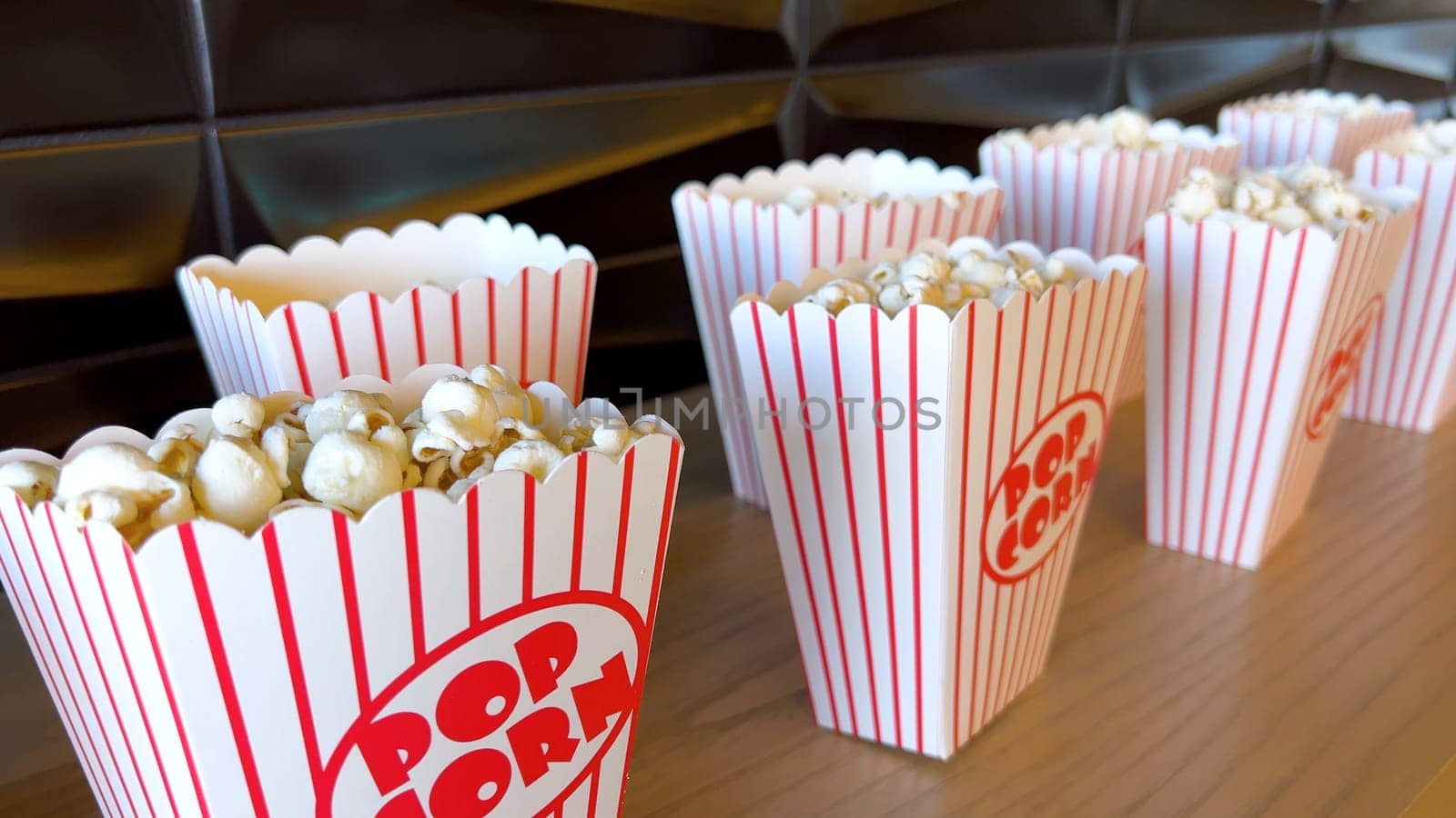 Rows of freshly filled striped popcorn boxes await eager moviegoers, their nostalgic design adding to the anticipation of entertainment.