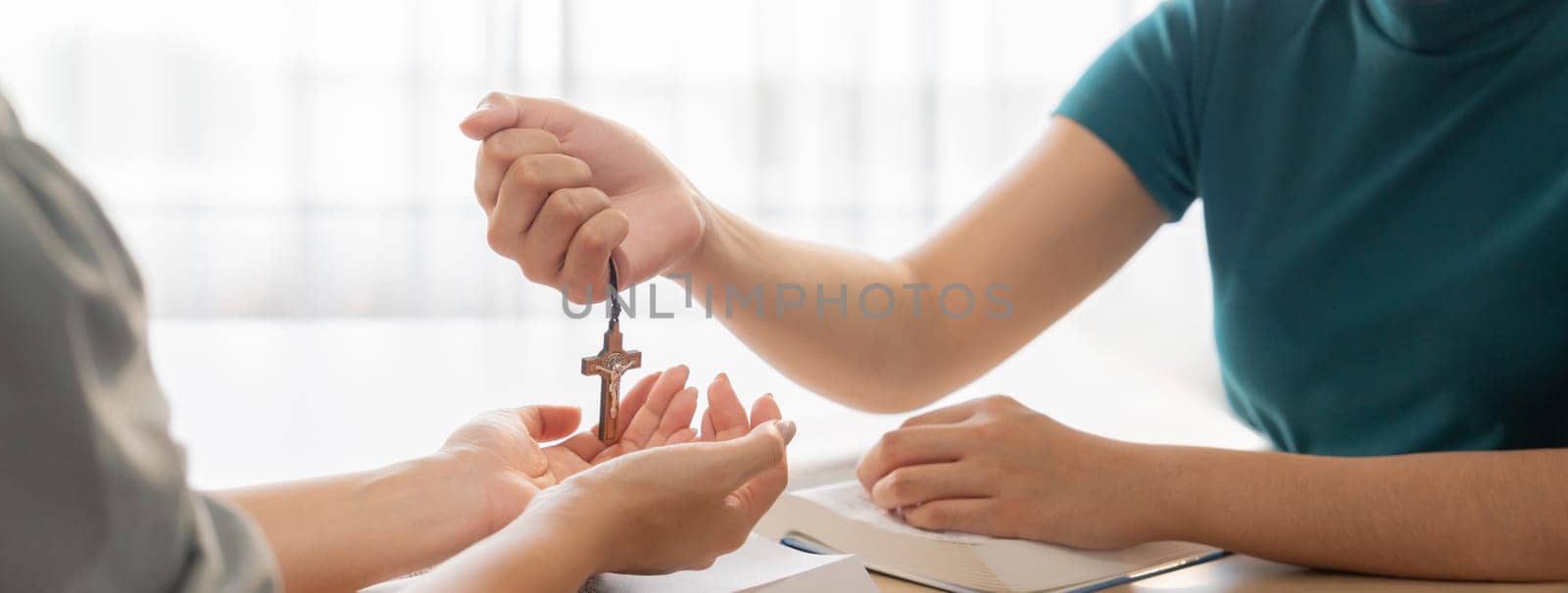 Close-up women prayer deliver holy bible book and holy cross to young believer. Spreading religion symbol. Concept of hope, religion, christianity and god blessing. Warm background. Burgeoning.