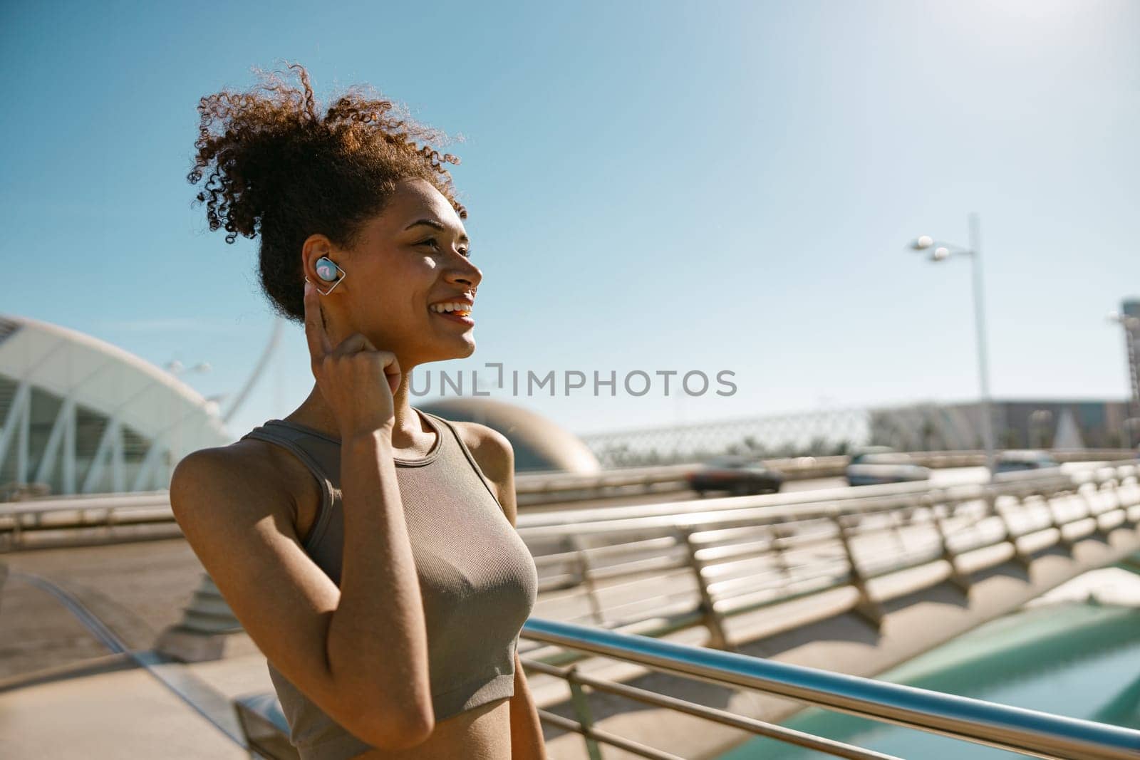 Smiling woman in sportswear have a rest after workout outside standing on bridge background