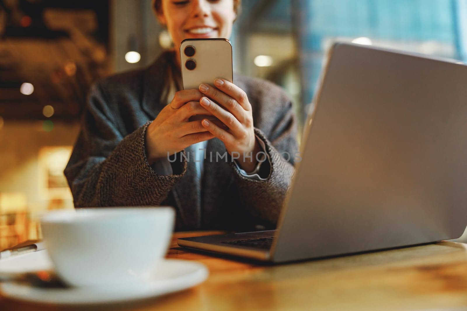 Smiling woman manager is using phone and work on laptop outside of office. Distance work concept