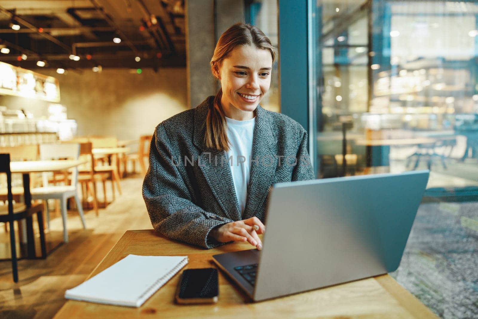 Stylish woman manager freelancer working on laptop while sitting in cozy cafe. High quality photo