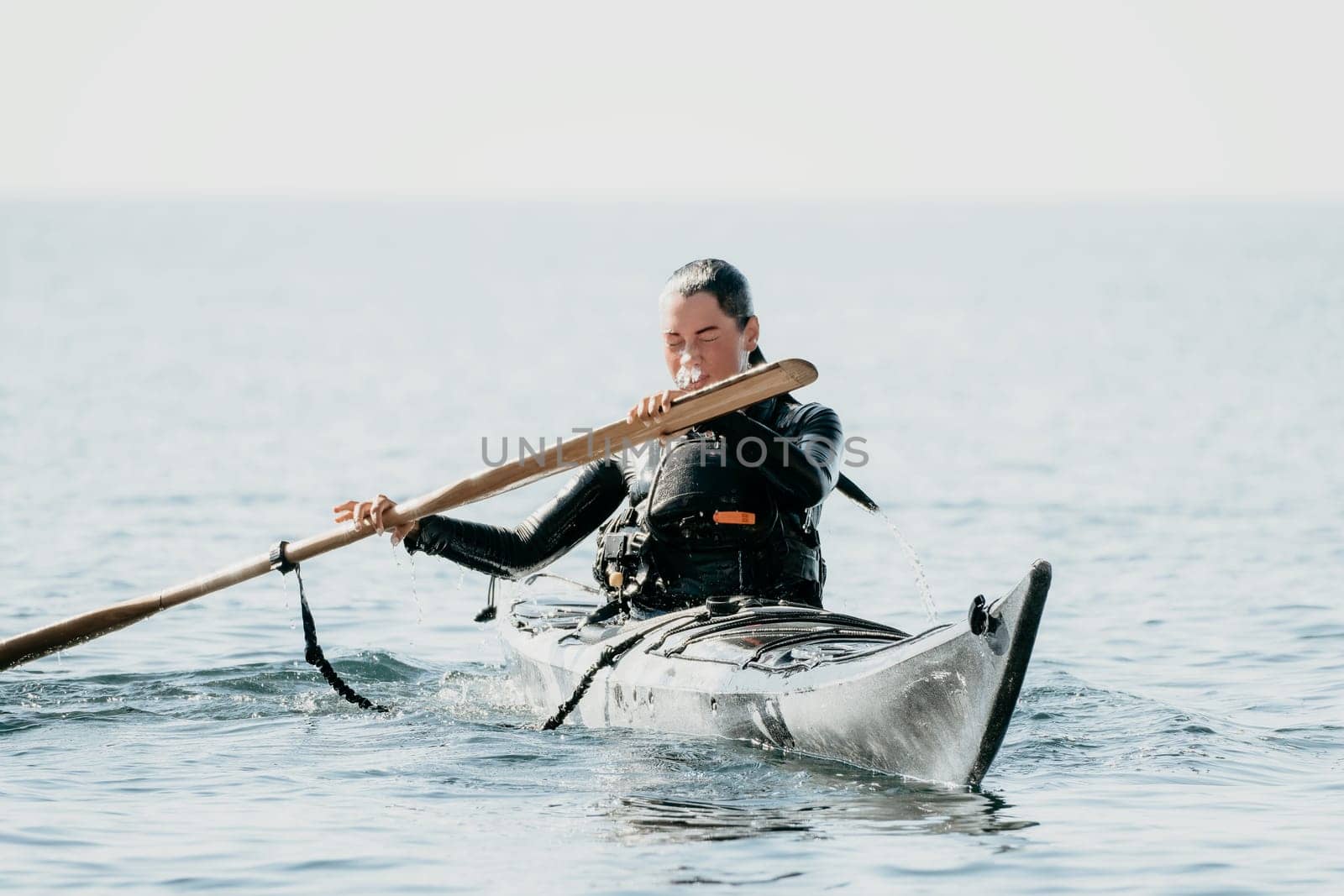 Woman sea kayak. Happy smiling woman in kayak on ocean, paddling with wooden oar. Calm sea water and horizon in background. Active lifestyle at sea. Summer vacation. by panophotograph