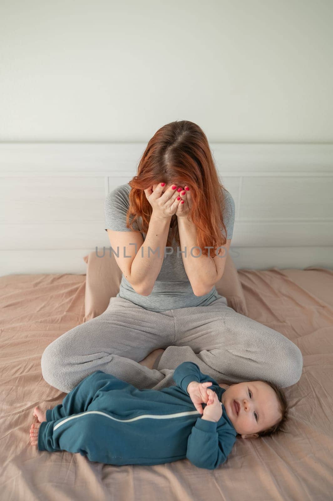 A woman sits on her child's bed and cries. Postpartum depression. Vertical photo