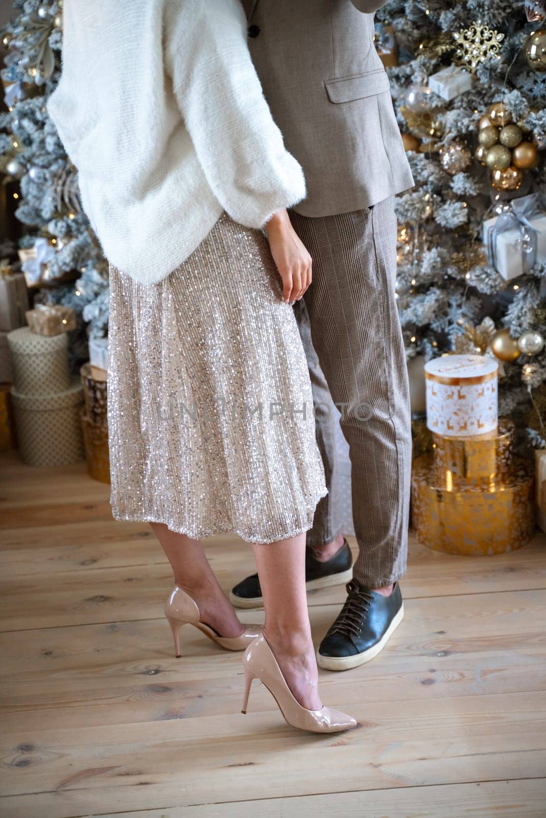 Romantic couple standing near Christmas tree at home and hugging.