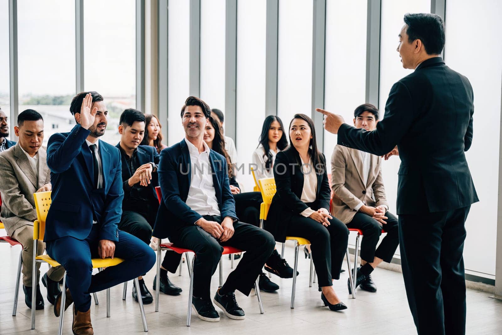 During a conference one young man's raised hand symbolizes active engagement teamwork and a desire to contribute to discussions.