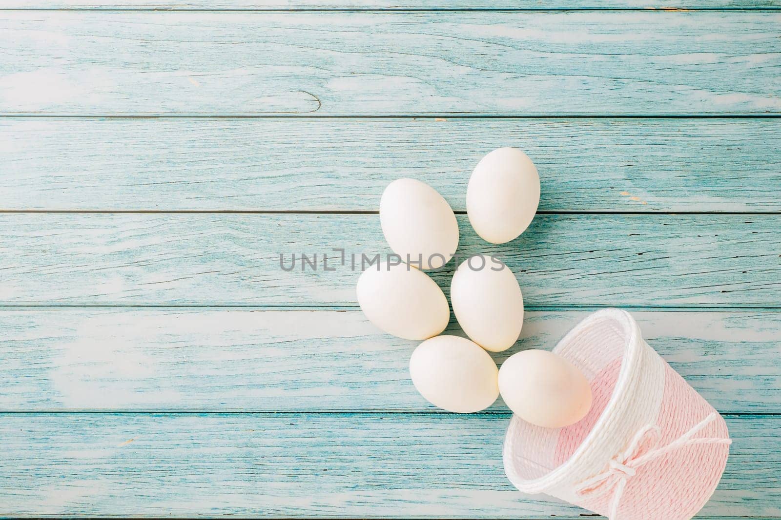 Happy Easter Day Concept. Top view of holiday banner background design white easter eggs and basket on blue wooden background with empty copy space, celebration greeting card