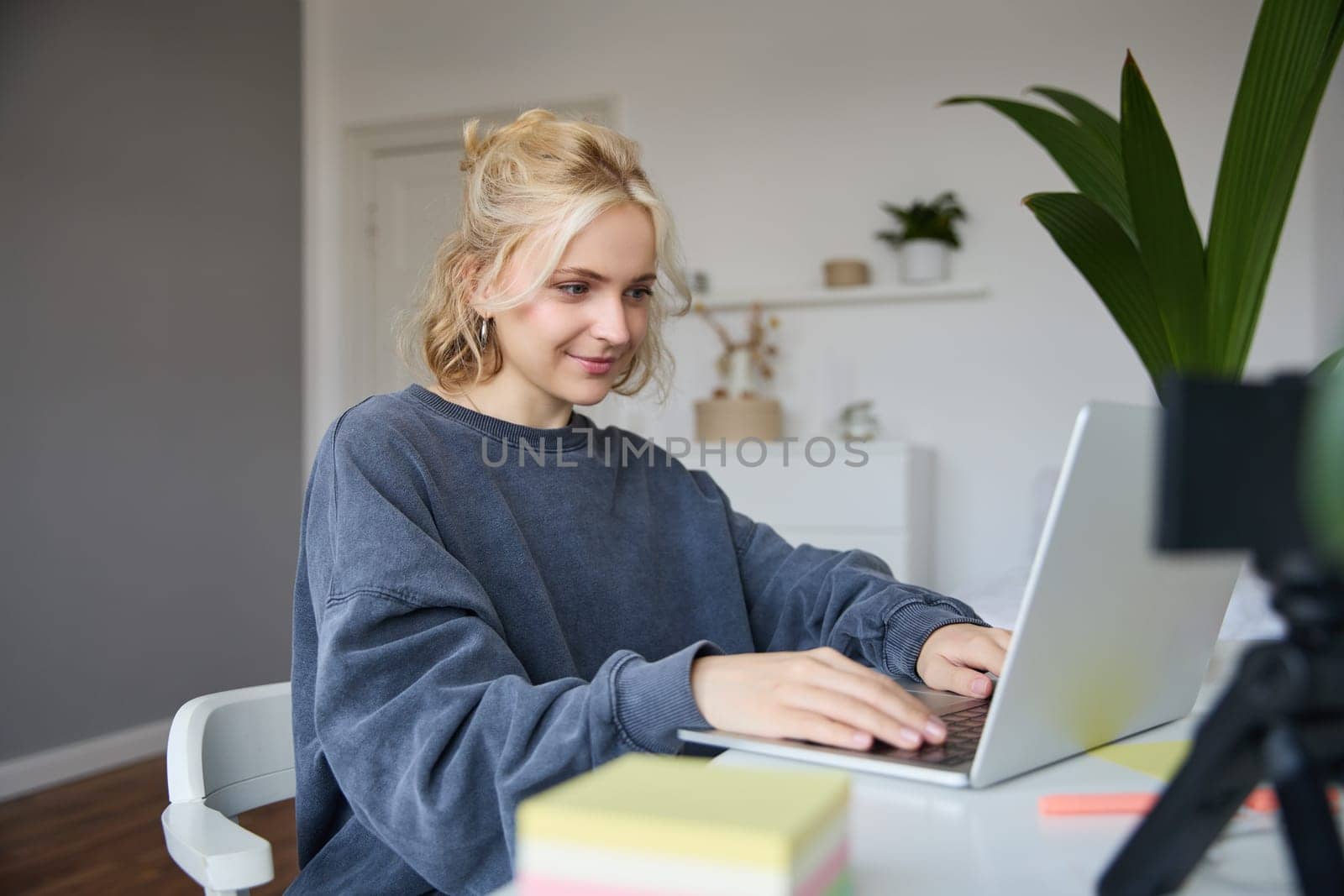 Portrait of young woman, student studying at home on remote education, working on laptop, typing on keyboard.