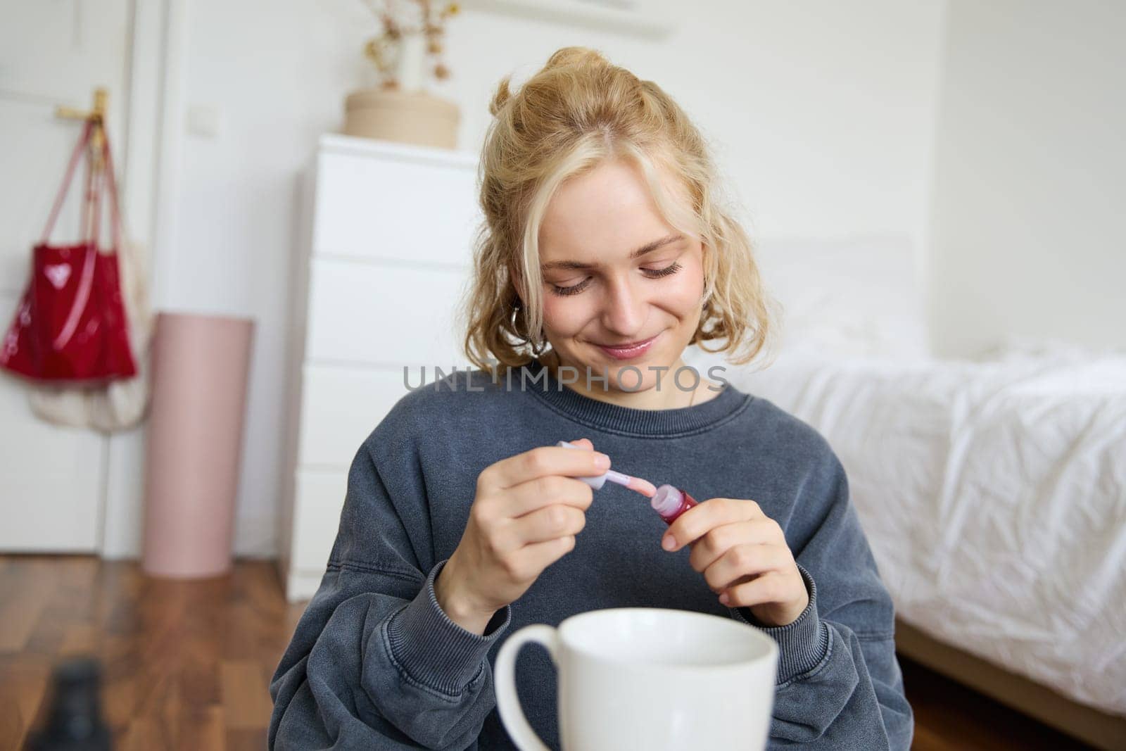 Portrait of smiling charismatic woman, puts on lip gloss, drinks tea, records video on digital camera, beauty content for social media account.