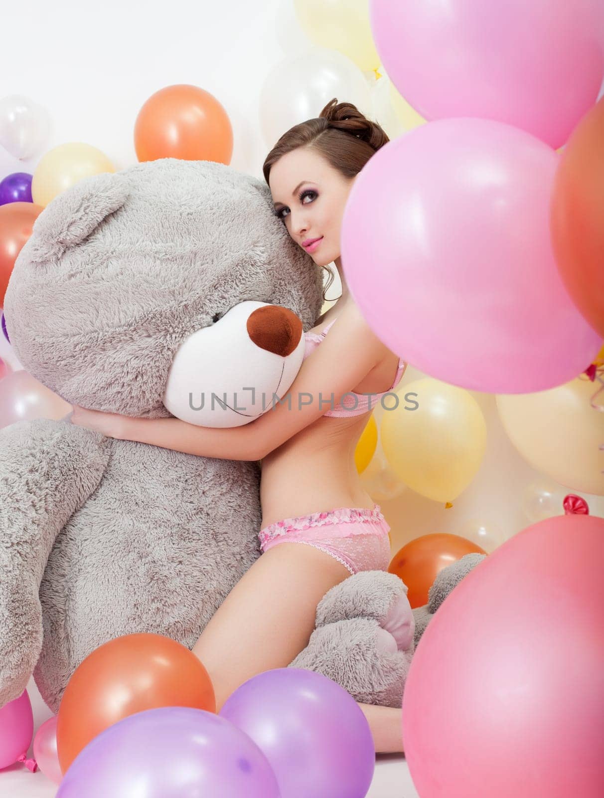 Image of sexy slender brunette hugging big teddy bear