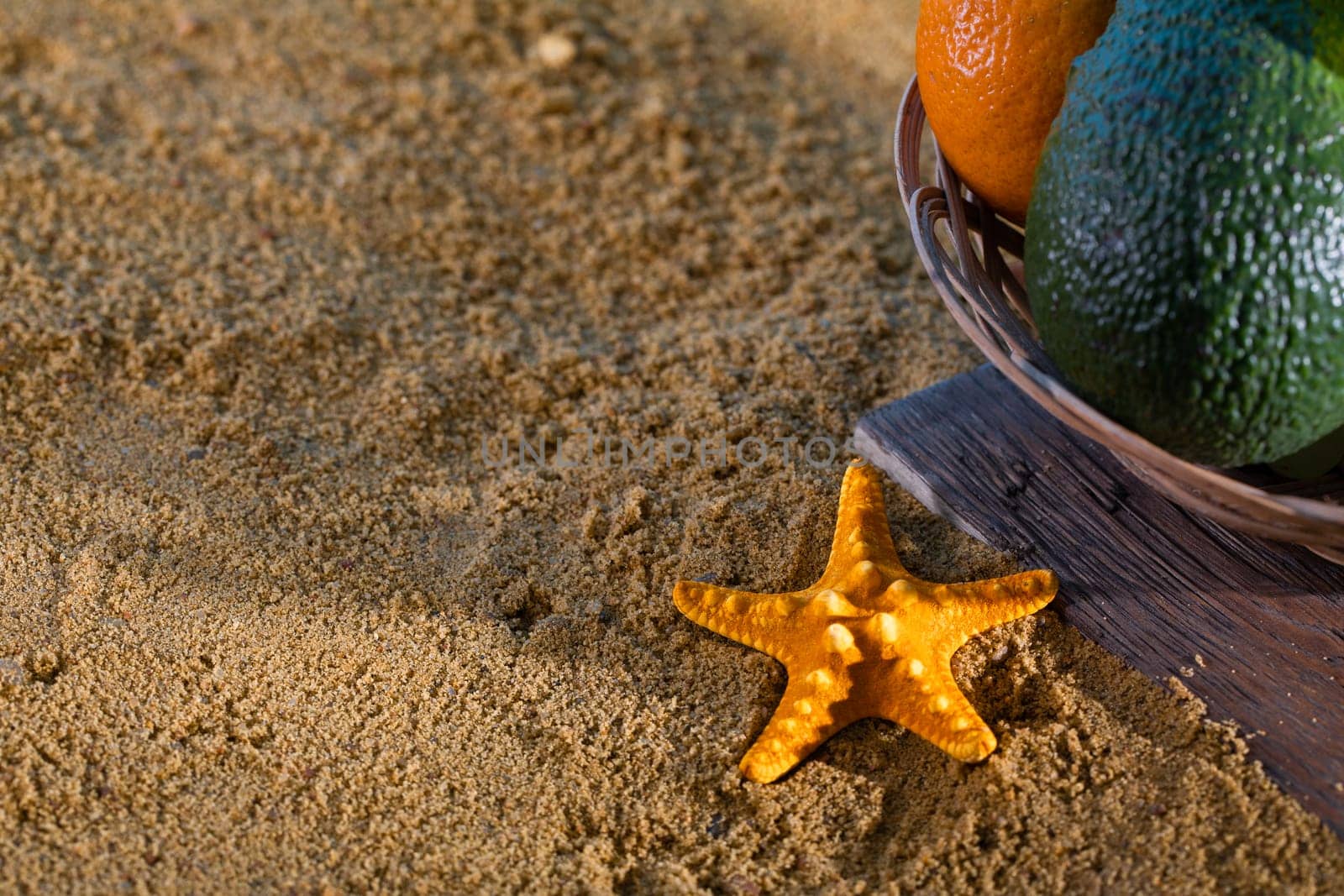 Fruit in a basket on a wooden board next to the sandy sea beach. The coast is full of wet squeak. by fotodrobik