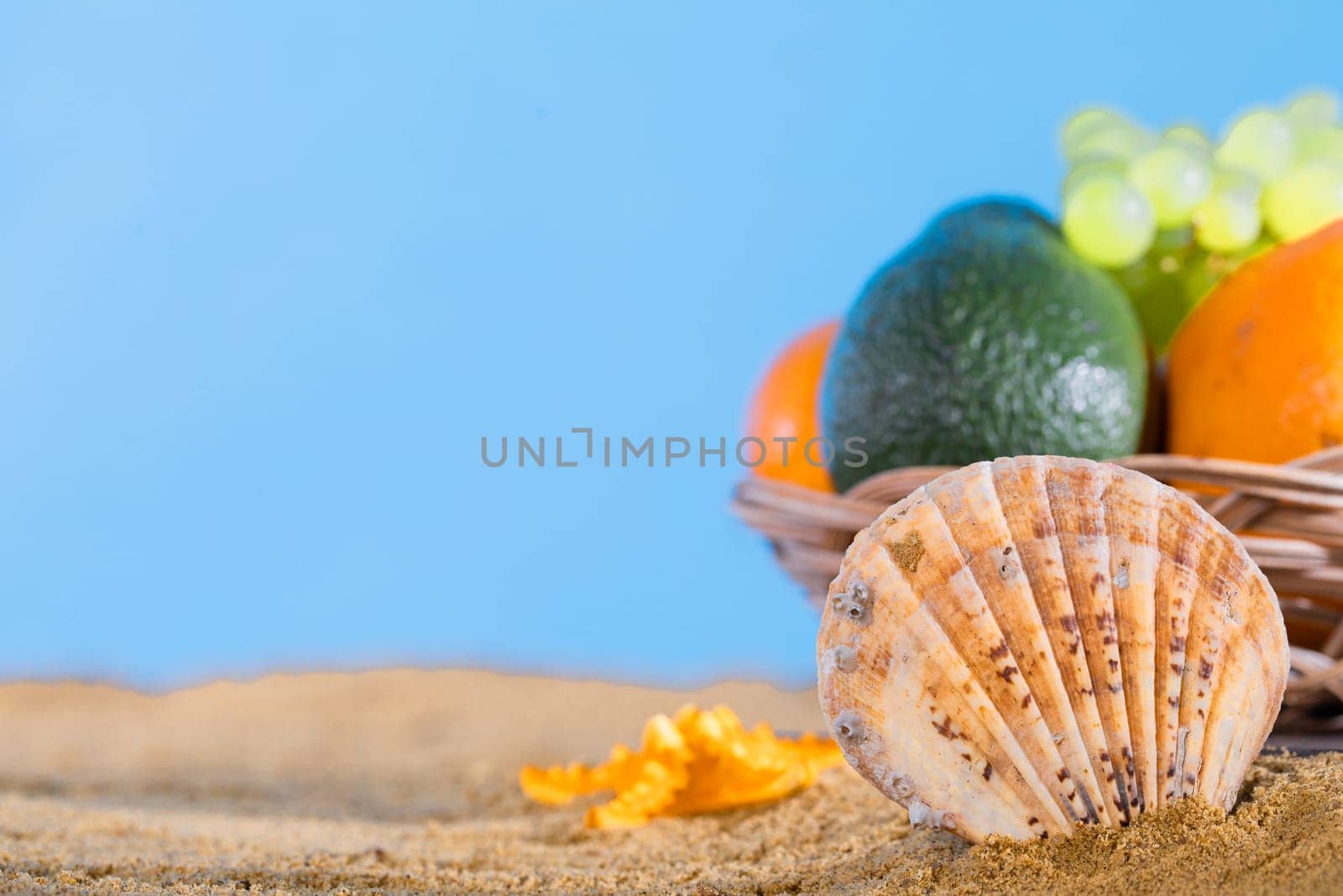 Blue sky over the sea beach. Ripe southern fruits lie in the basket. Sea shore of a sandy beach.