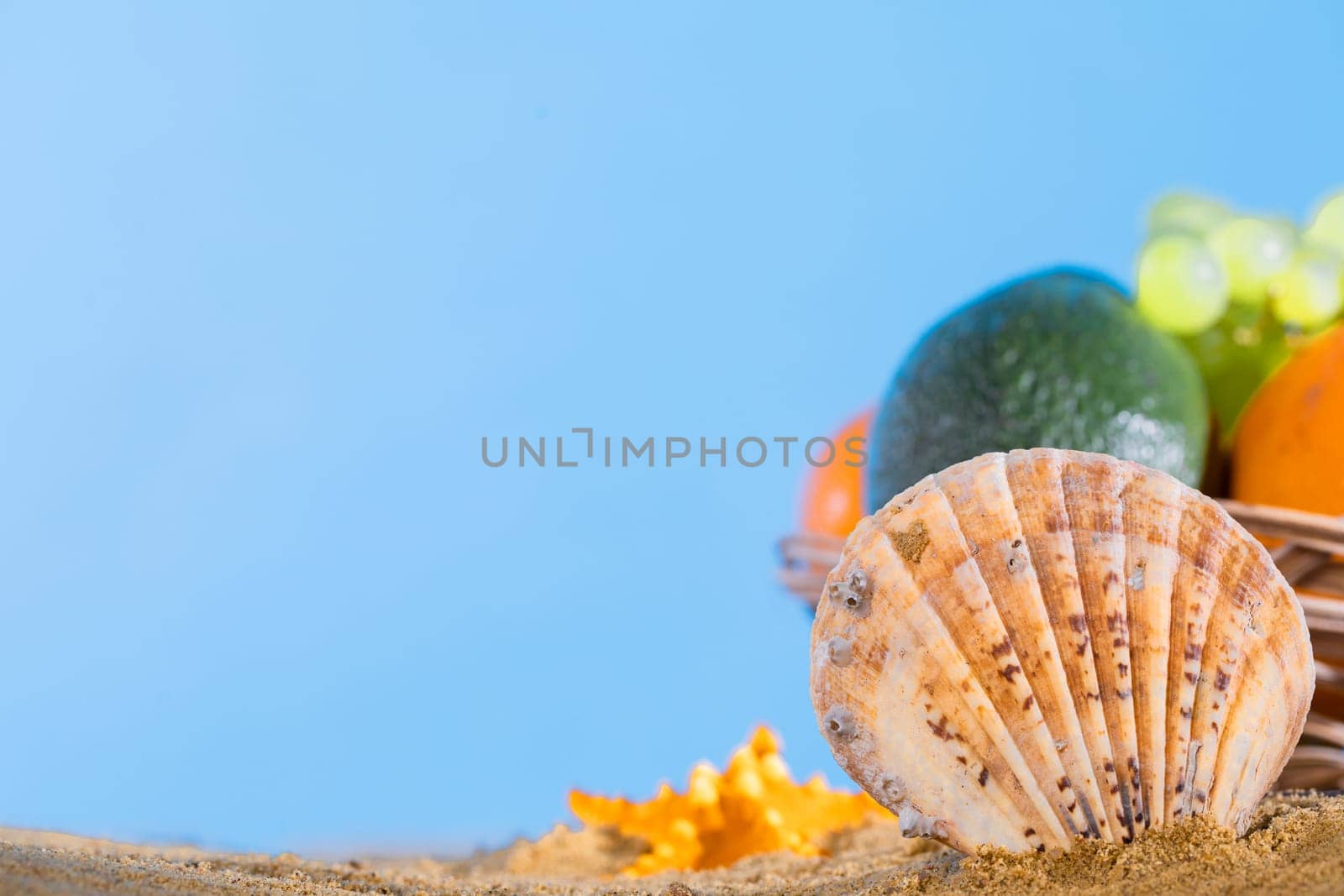 Against the blue sky in the basket right on the sandy sea beach lies fruit. The coast is full of wet squeak. by fotodrobik