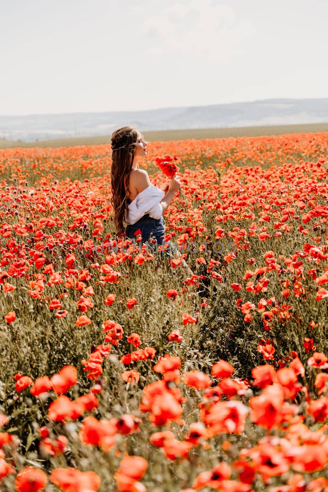 Woman poppies field. Side view of a happy woman with long hair in a poppy field and enjoying the beauty of nature in a warm summer day. by Matiunina
