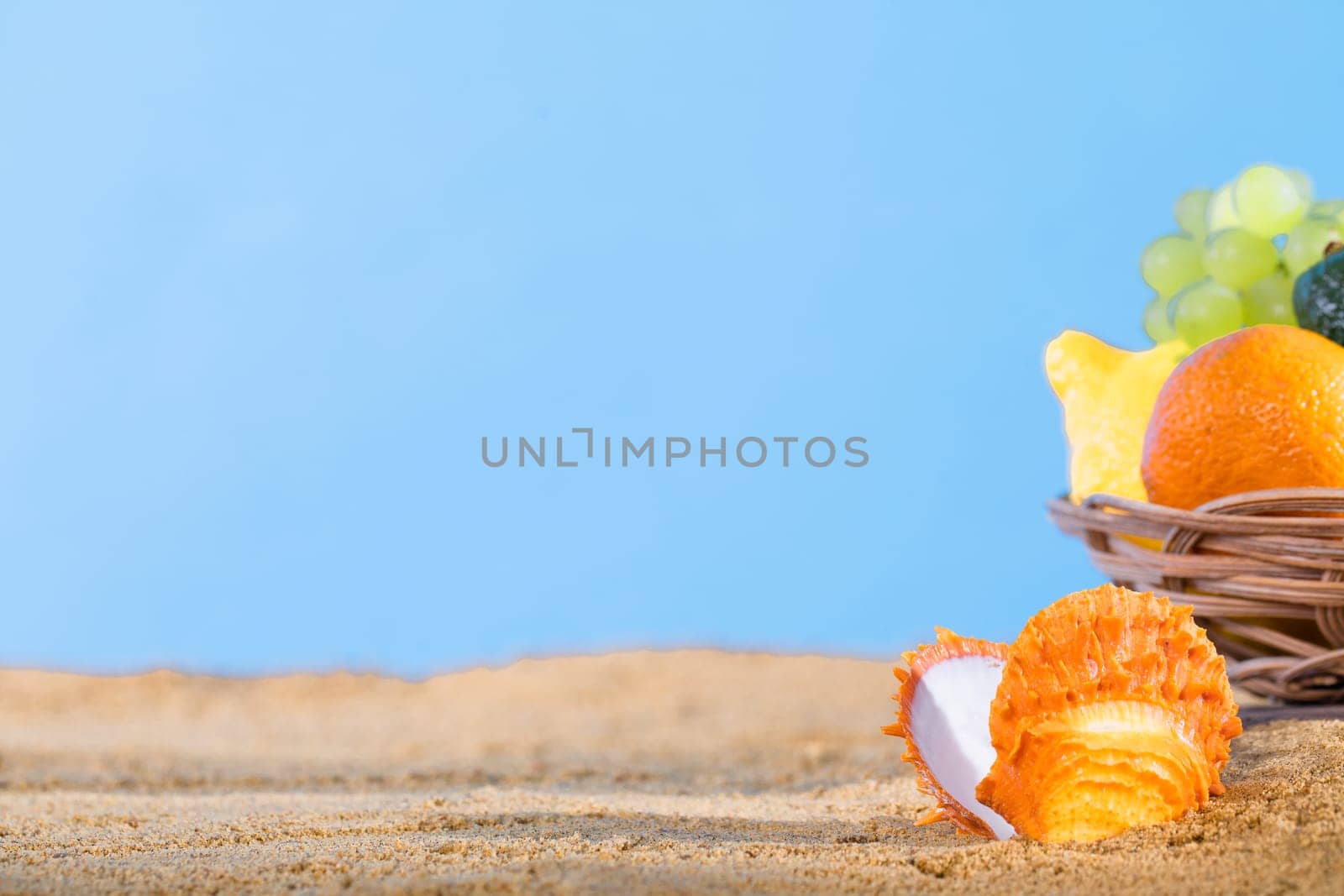 Against the blue sky in the basket right on the sandy sea beach lies fruit. The coast is full of wet squeak. by fotodrobik