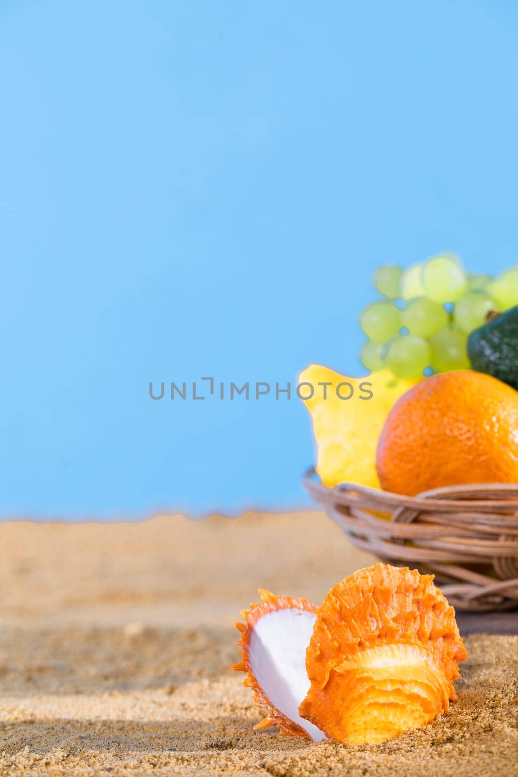 Blue sky over the sea beach. Ripe southern fruits lie in the basket. Sea shore of a sandy beach.