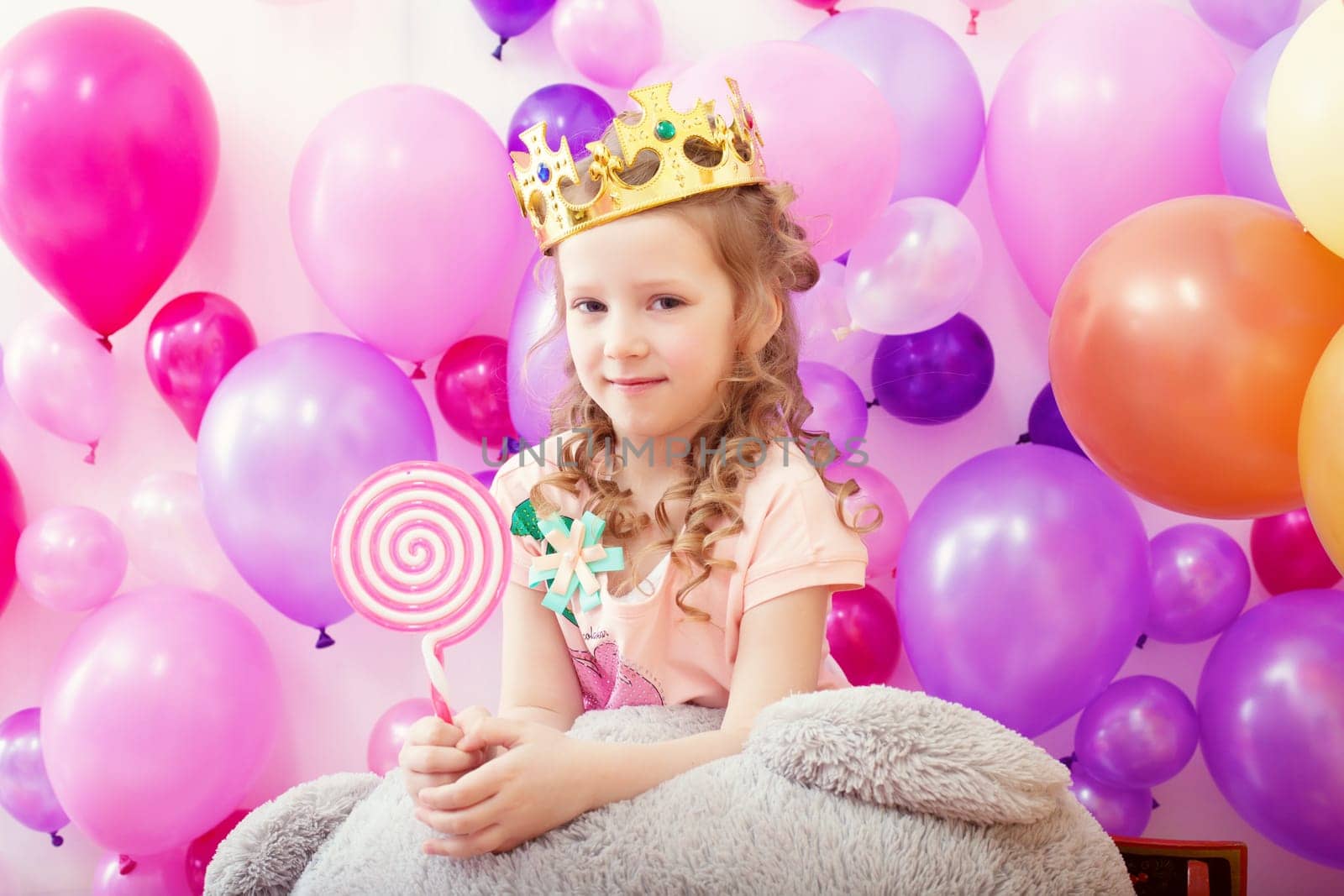 Image of lovely curly girl posing in crown with lollipop