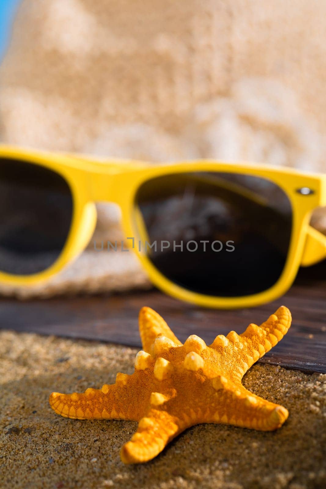 A summer hat and sunglasses lie on the sandy coast of the sea beach.