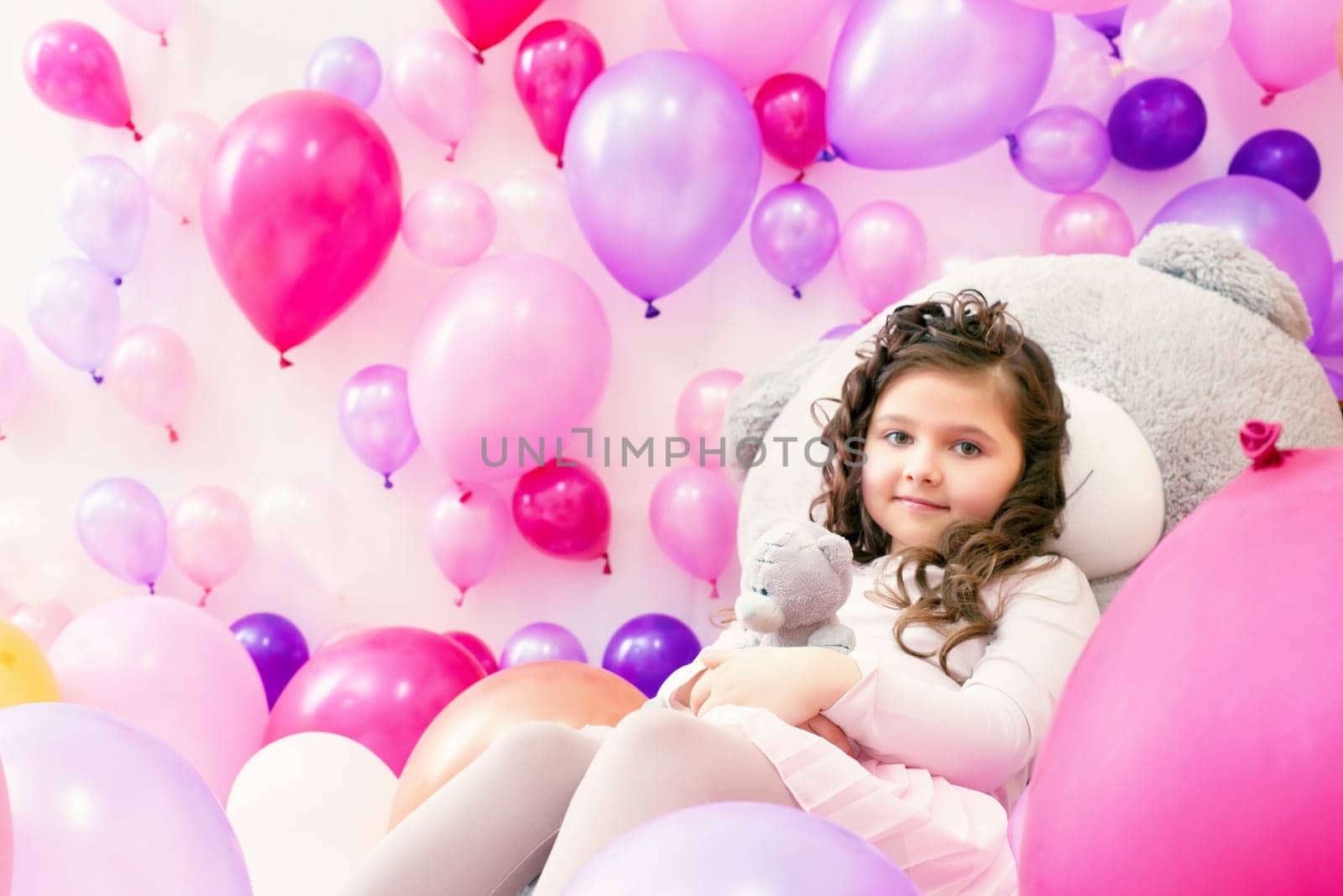 Playful little girl posing in studio with colorful balloons