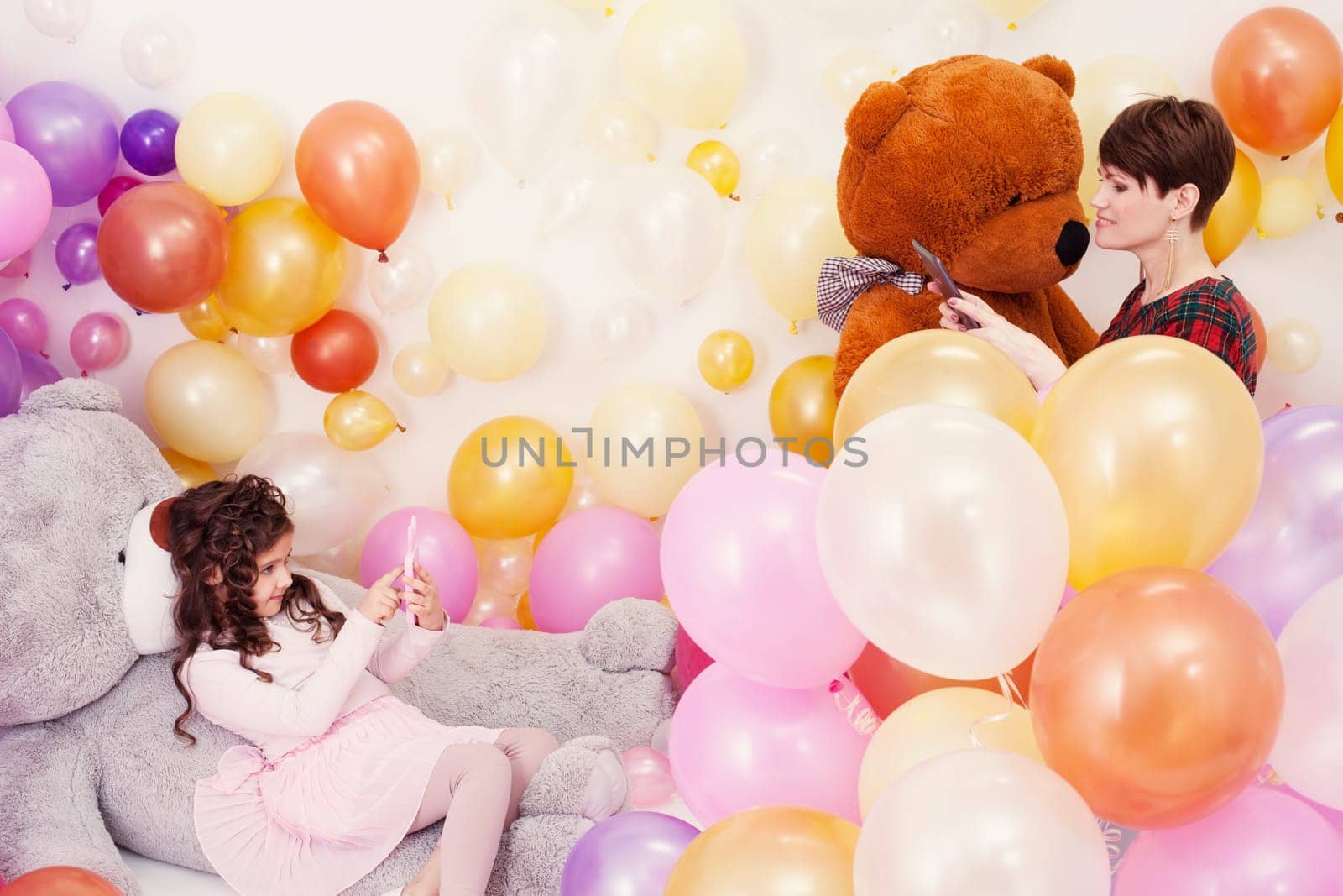Elegant mother photographed her charming daughter in studio with balloons