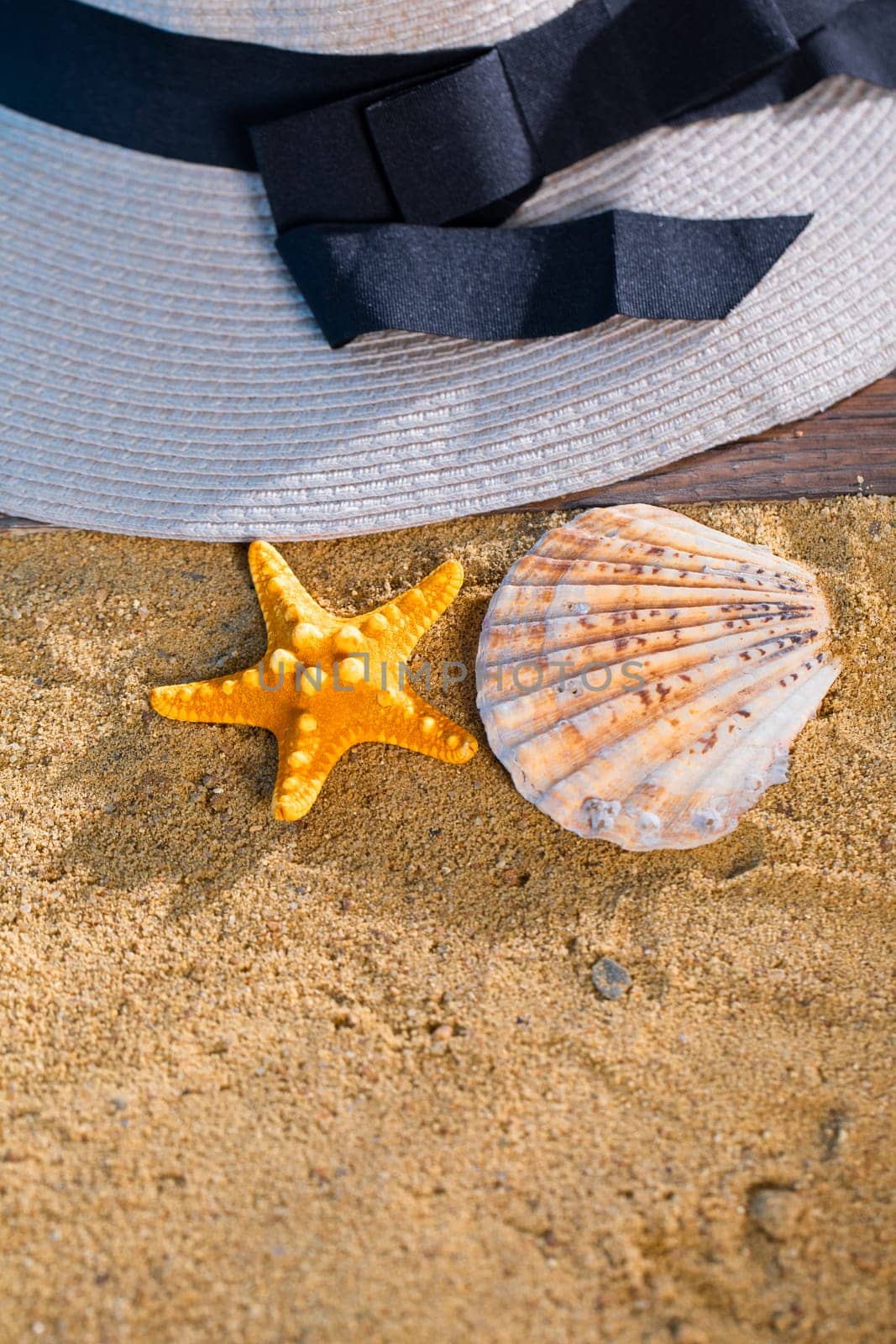 Summer hat lie on the sea beach. Sunny sandy coast next to the sea. by fotodrobik