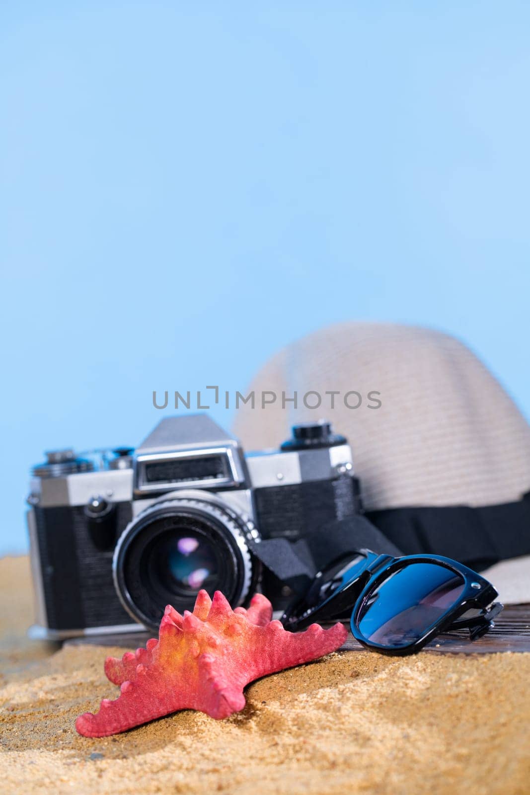 Blue sky. Old photographic film camera. Sunglasses. Sandy sea beach. Summer hat.