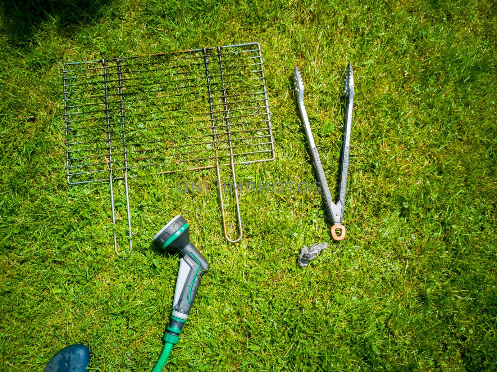 BBQ grillage rost lying on the wet lawn.