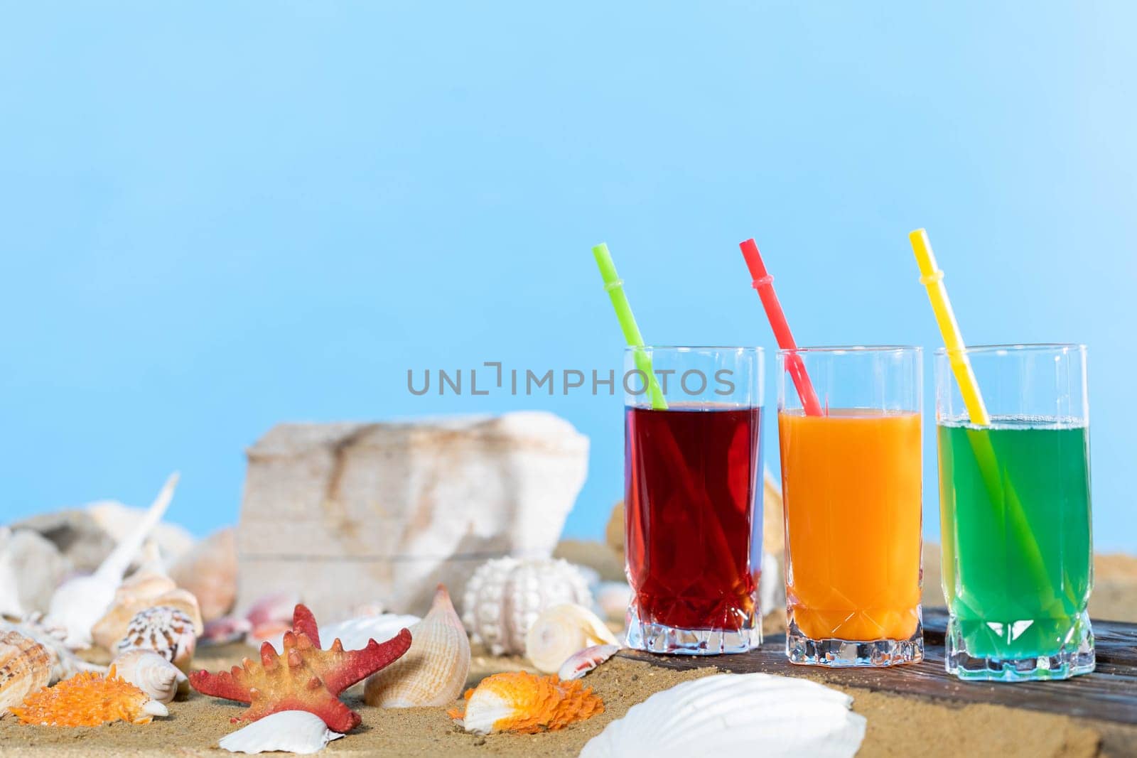 Fresh fruit juice in a tall glass. Shore of a sandy beach on a cool sea.