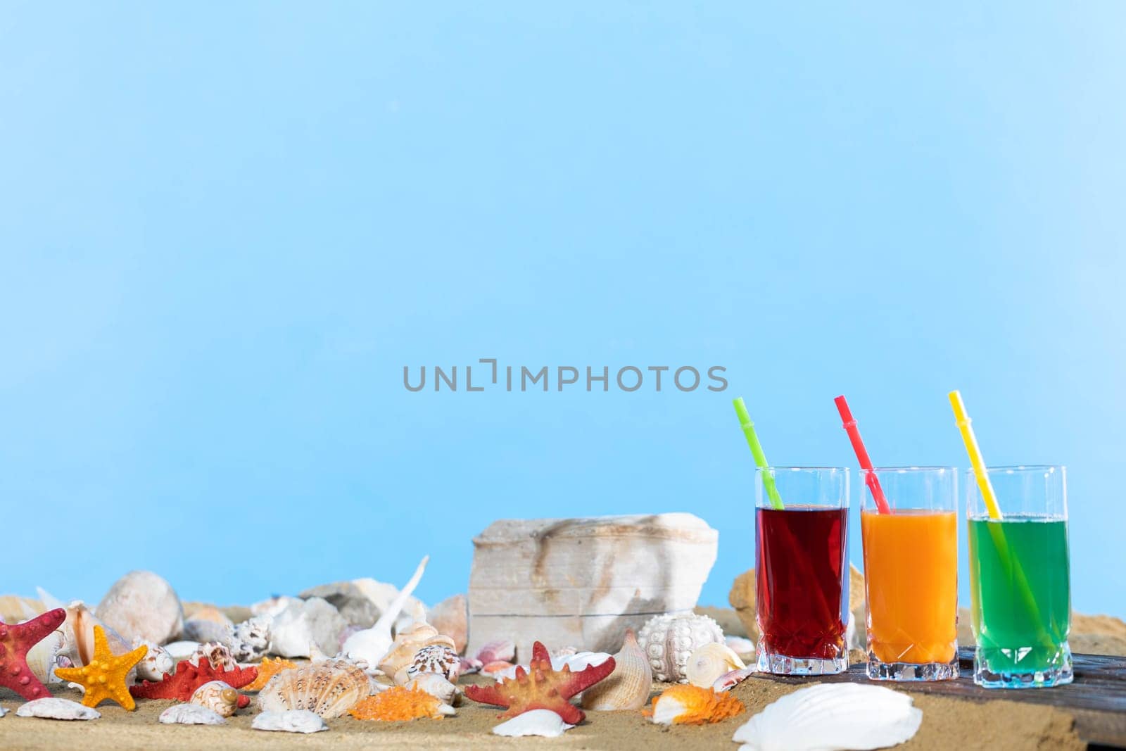 Fresh fruit juice in a tall glass. Shore of a sandy beach on a cool sea.