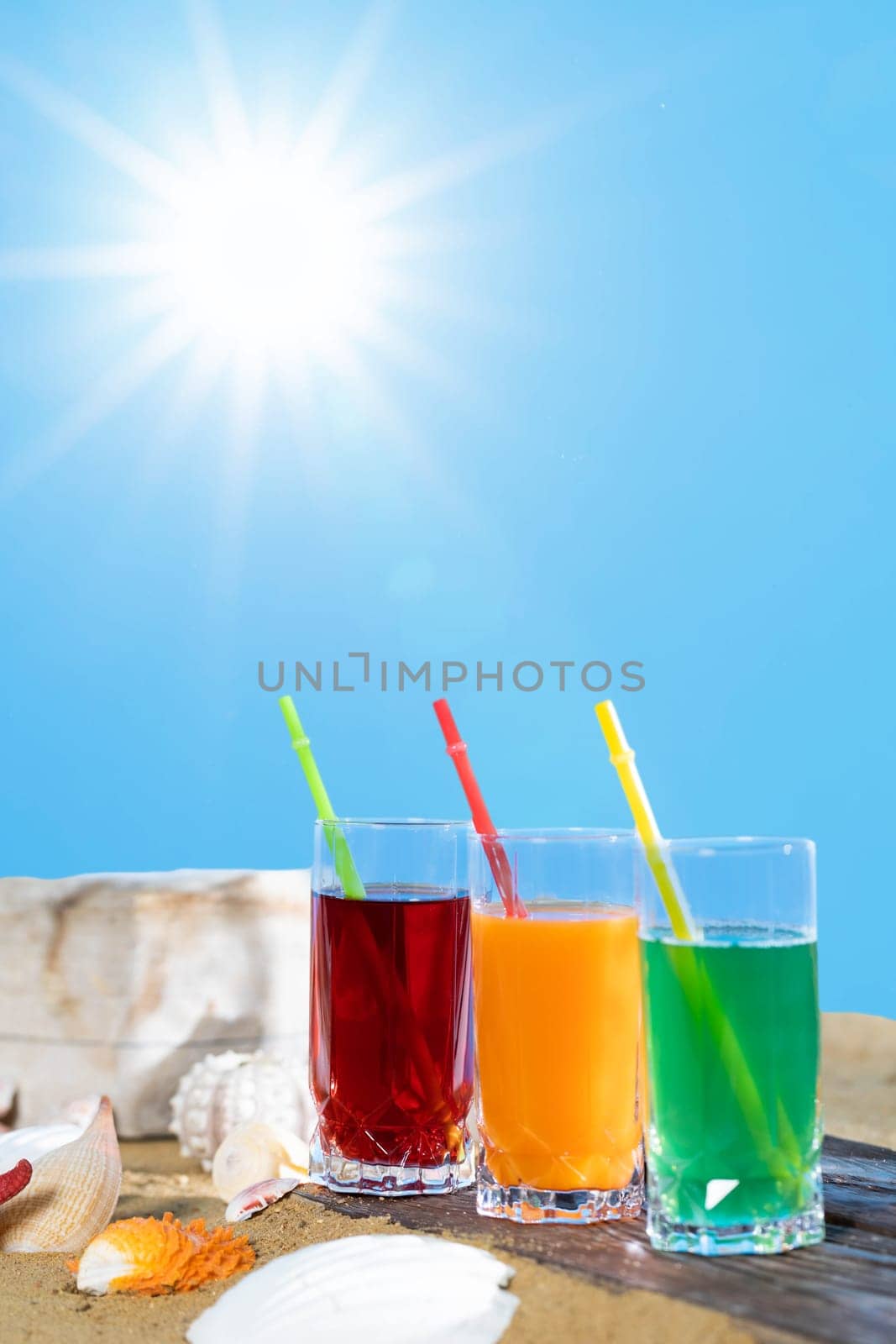 Ulane summer while on vacation. Sandy beach dotted with empty snail shells. Fresh fruit juice.