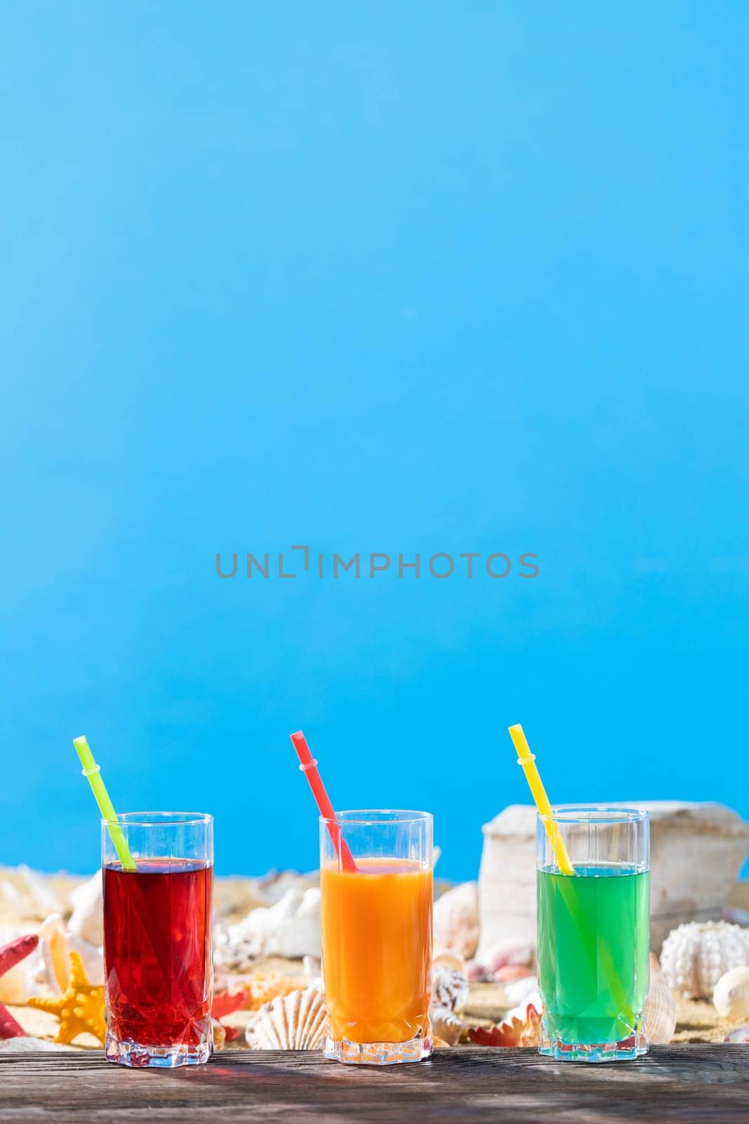 Fresh fruit juice in a tall glass. Shore of a sandy beach on a cool sea.