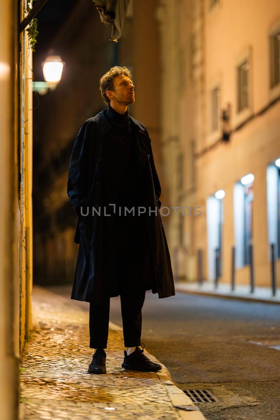 A man in black suit in a city street at night - vertical