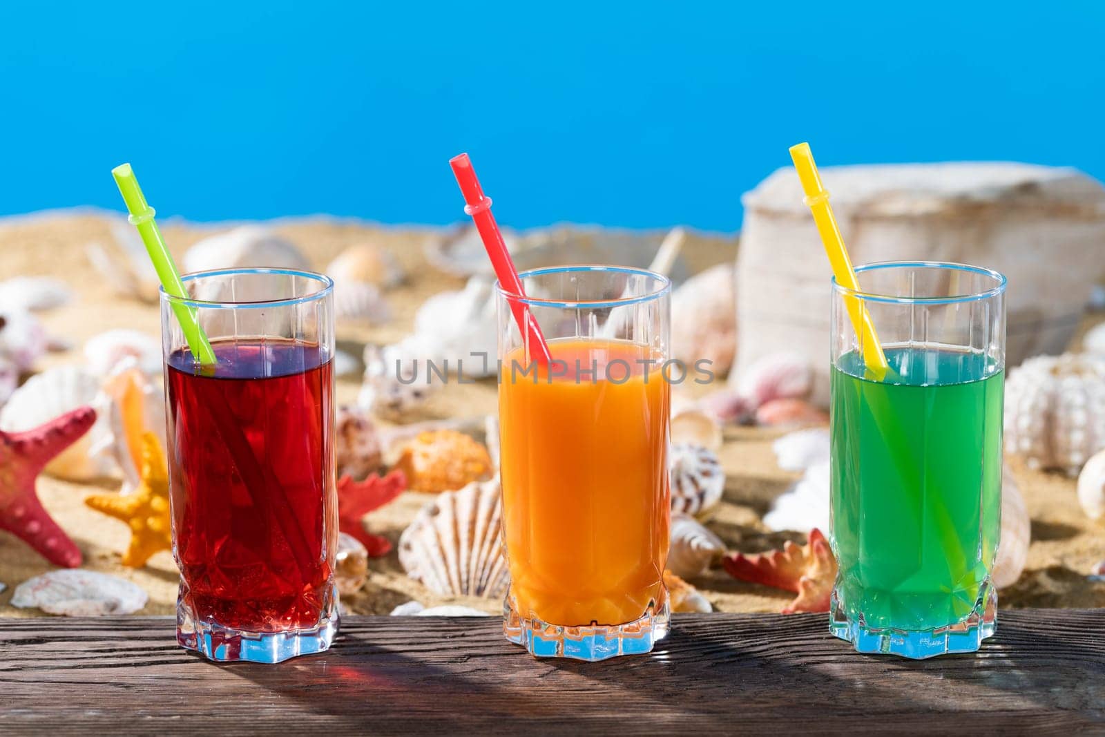 Fresh fruit juice in a tall glass. Shore of a sandy beach on a cool sea.